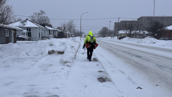 Un postier de Postes Canada marche sur une rue enneigée à Sept-Îles