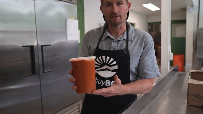 un homme tient un contenant de sauce ratatouille.