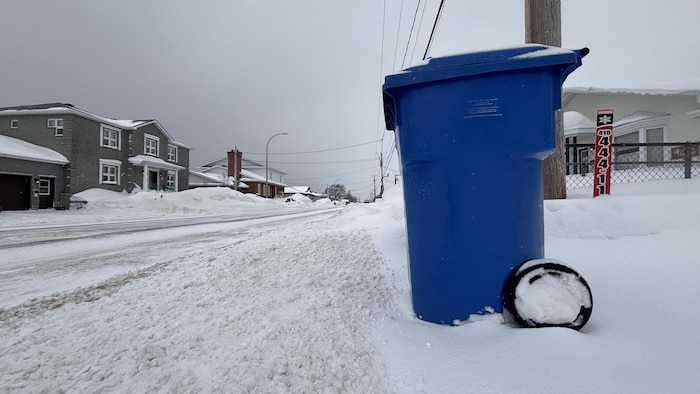 Une poubelle dans une rue enneigée.