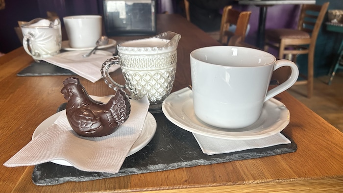 Une poule au chocolat et un breuvage chaud sur une table d'un café.