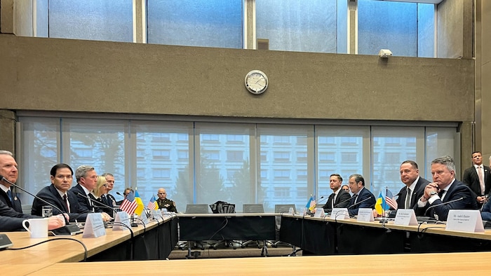 Des diplomates assis à une table carrée.