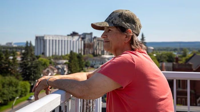  Une femme, debout à l'extérieur, contemple son quartier.