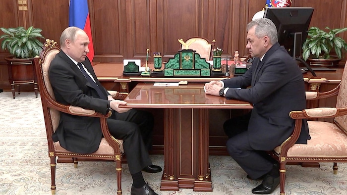 Vladimir Poutine et Sergueï Choïgou, assis de part et d'autre d'une table.
