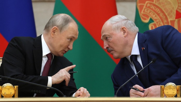 Le président russe, Vladimir Poutine, et le président bélarusse, Alexandre Loukachenko, discutent assis à une table. 