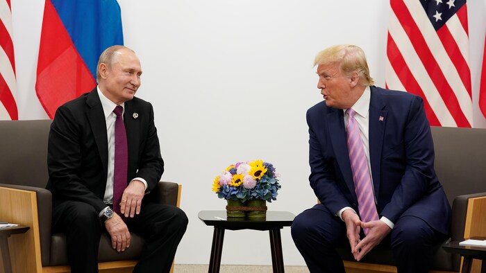 Vladimir Poutine et Donald Trump, légèrement penché vers son homologue, se sourient.