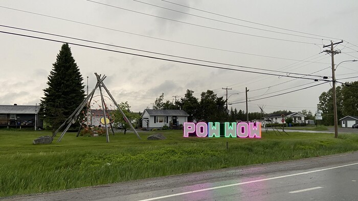 Des lettres illuminées forment les mots Pow Wow. Un tipi est placé tout près sur un terrain de Pikogan.