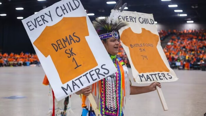 Malaki Kennedy tient deux affiches du mouvement Every child matters.