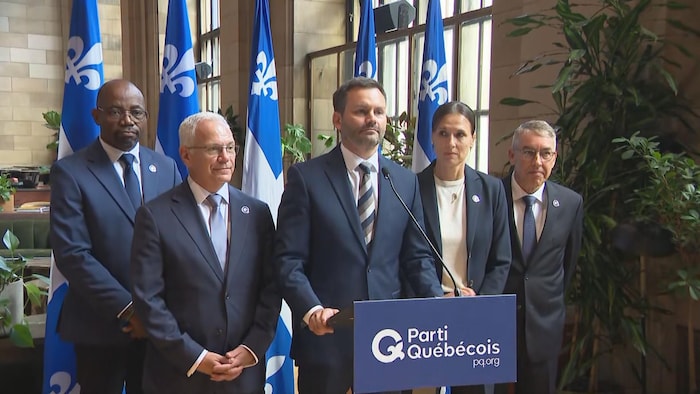 Cinq personnes derrière un lutrin lors d'une conférence de presse.