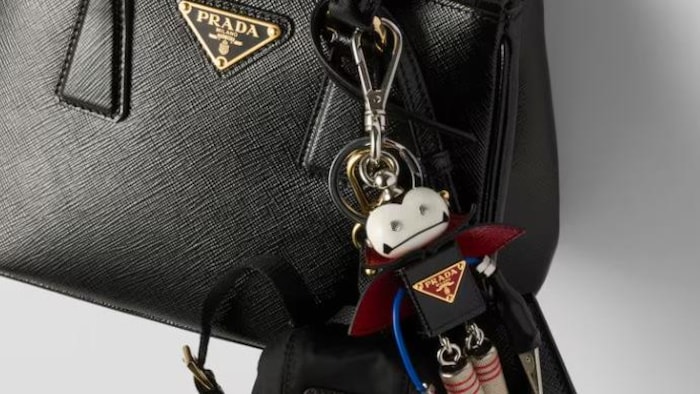 Un sac à main de la marque Prada sur lequel est suspendu un porte-clés en forme de robot.