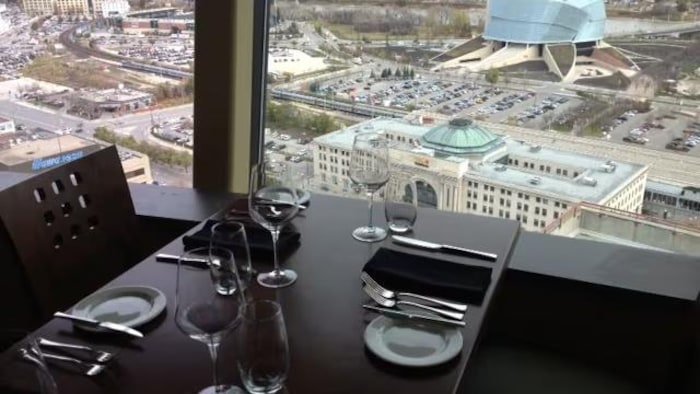 Une table de restaurant à côté d’une fenêtre qui donne sur le centre-ville de Winnipeg.