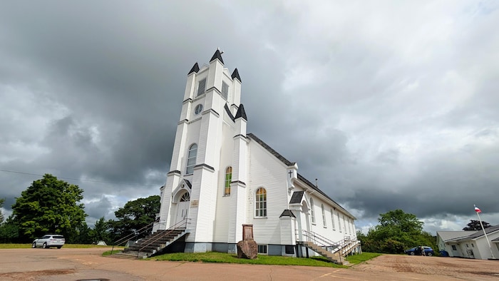 Une église blanche sous un ciel gris et menaçant.
