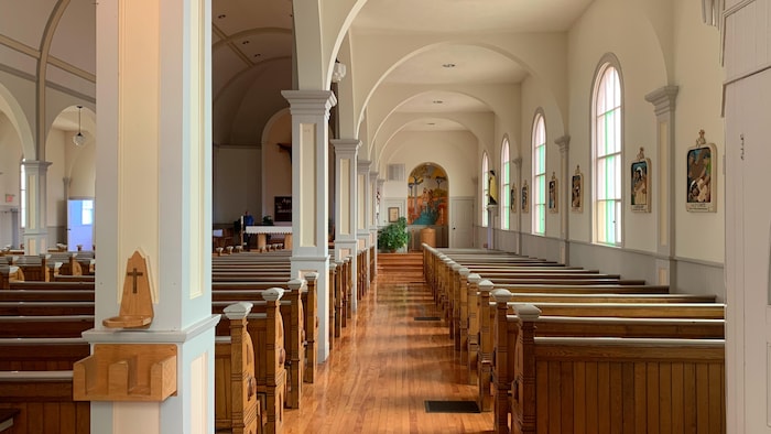 Des rangées de bancs à l'intérieur de l'église et de grandes fenêtres qui laissent entrer la lumière.