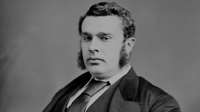 Sir John Sparrow David Thompson pose assis sur une photo d'archive.