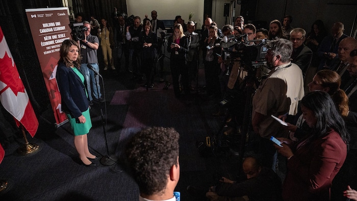 La première ministre de l'Alberta, Danielle Smith, entourée de journalistes.