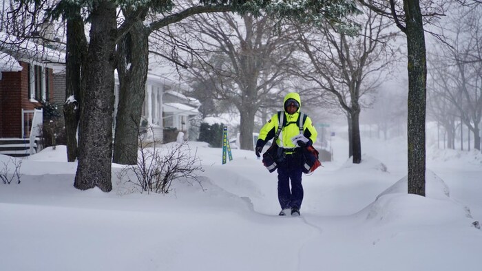 Un facteur qui marche avec son courrier dans la tempête de neige.