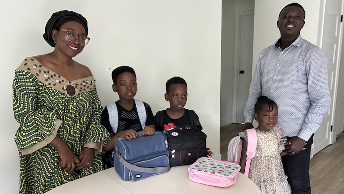 Une famille debout à l'intérieur d'une maison. 