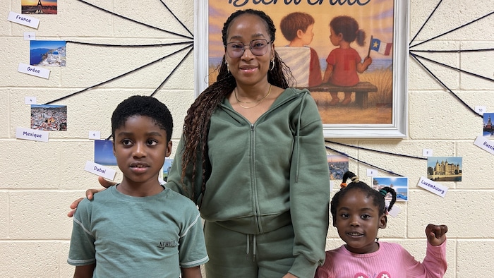 Une famille pose devant un tableau. 