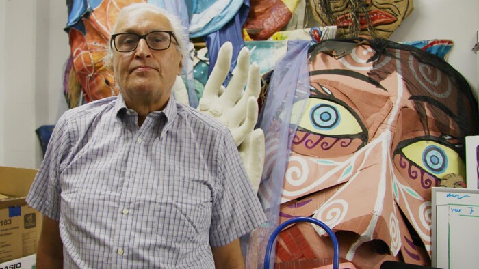André Dudemaine pose devant des éléments décoratifs inspirés de la culture autochtone.