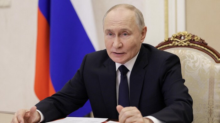  Vladimir Poutine assis, lors d'une réunion.