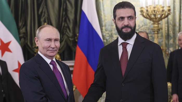 Vladimir Poutine et Ahmad al-Chareh se serrent la main.