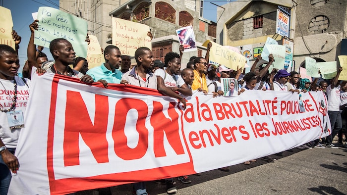 Des journalistes manifestant derrière une grande banderole.