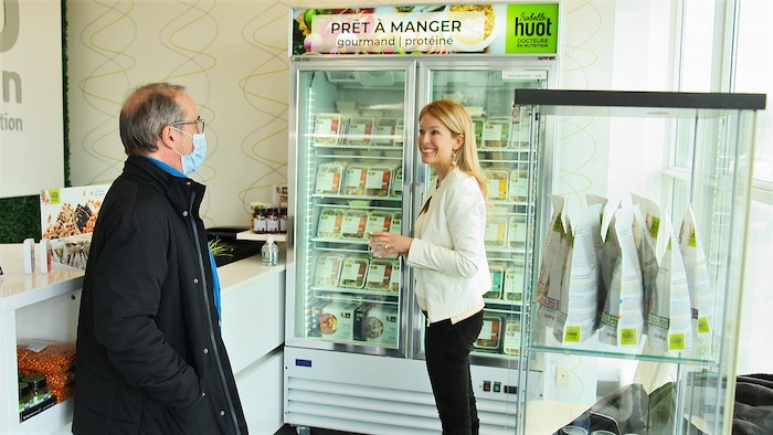 Denis Gagné et Isabelle Huot devant un réfrigérateur contenant des plats de prêt-à-manger.
