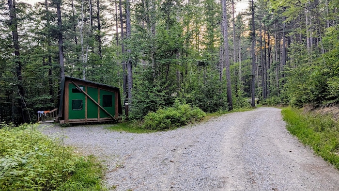 Une route en gravelle mène à une cabine en bois et en toile.