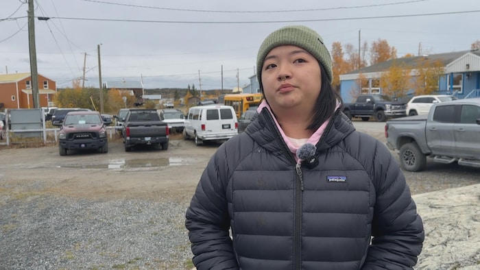 Une femme parle dans un micro devant un stationnement à Yellowknife.