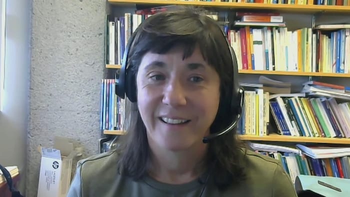 Une femme portant un casque d'écoute fixe l'écran lors d'une entrevue en visioconférence