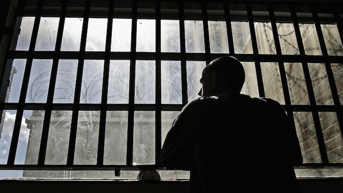 Un homme regarde par la fenêtre d'une prison.