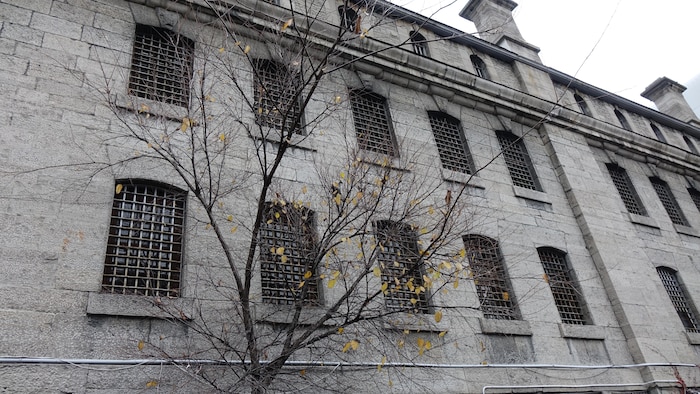 Un édifice de pierre gris sur lequel toutes les fenêtres ont des barreaux.