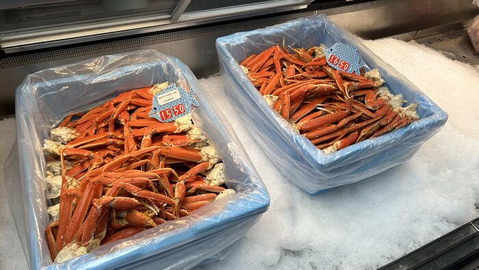 Des bacs remplis de pattes de crabes des neiges, dans un comptoir de poissonnerie.