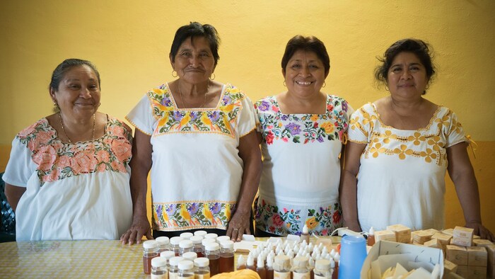 Cuatro mujeres mayas posan frente a productos elaborados a base de miel.