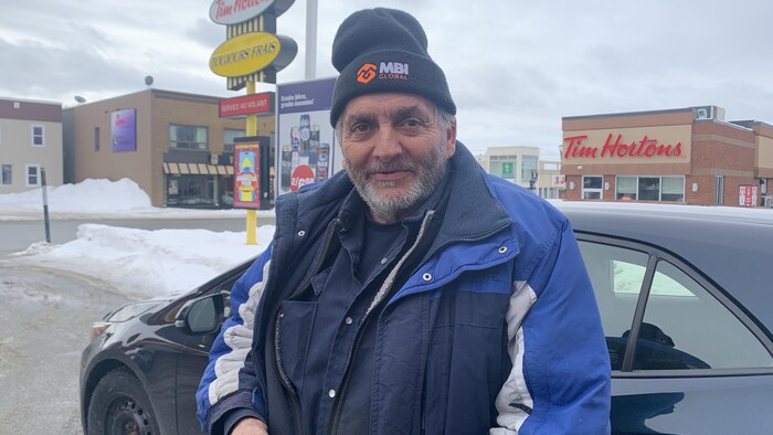 Onil Boucher regarde l'objectif en posant près d'une voiture.
