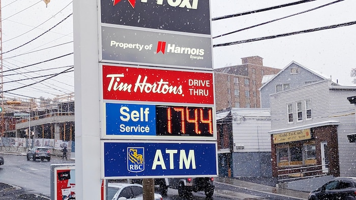 Sous la neige, l'enseigne d'une station-service indique que l'essence est à 174,4 cents le litre.