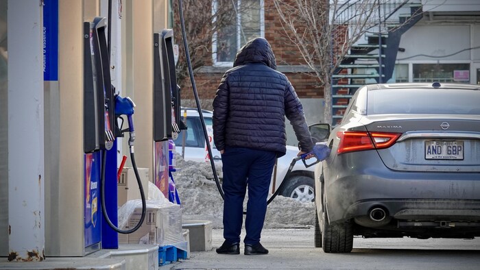 Un homme met de l'essence dans sa voiture.