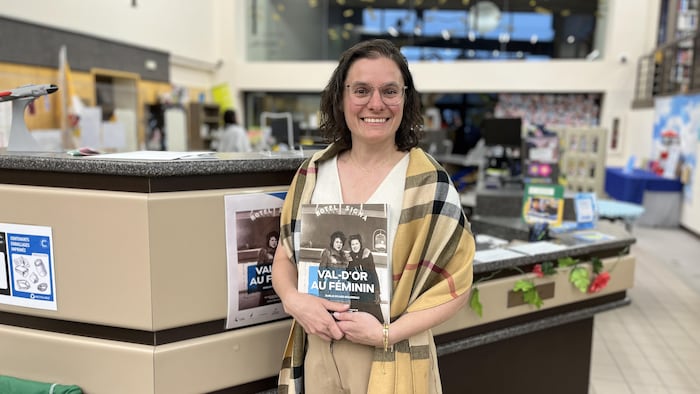 Émélie Rivard-Boudreau tient son livre Val-d'Or au féminin dans la bibliothèque municipale de Val-d'Or.