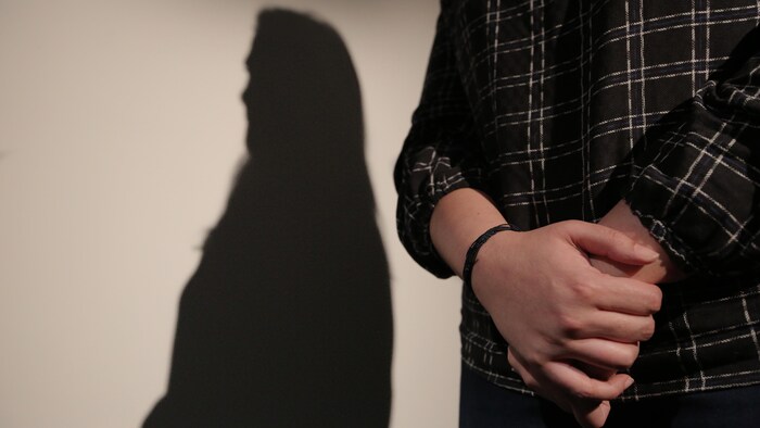Les mains d'une femme et son ombre sur un mur.