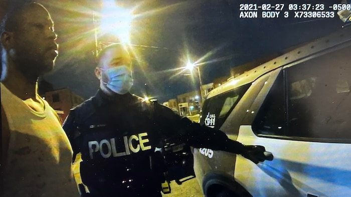 Leahain Malcolm devant une auto-patrouille de police.