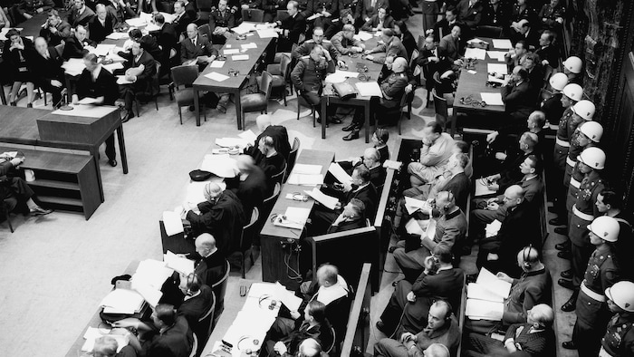 Sur cette photo d'archives du 20 novembre 1945, la police militaire garde la salle d'audience lors de la première séance du matin à Nuremberg. Au premier plan, les accusés; leurs avocats sont assis devant eux.