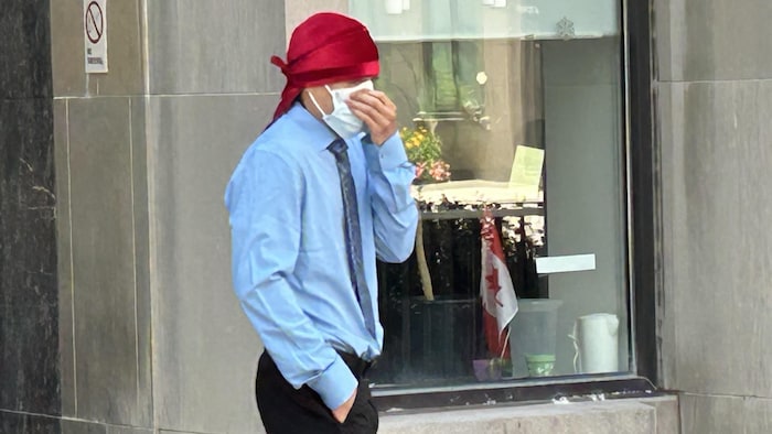 Un homme masqué devant un tribunal.