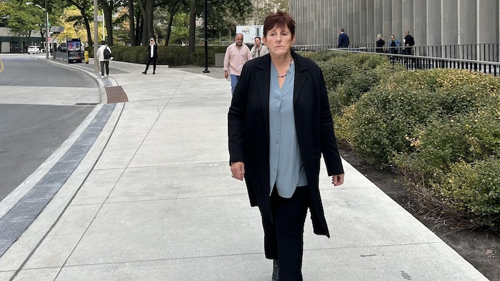 Une femme marchant sur un trottoir devant un tribunal.