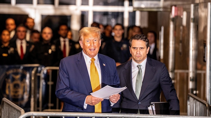 Donald Trump, aux côtés de son avocat Todd Blanche, tient des feuilles de papier.