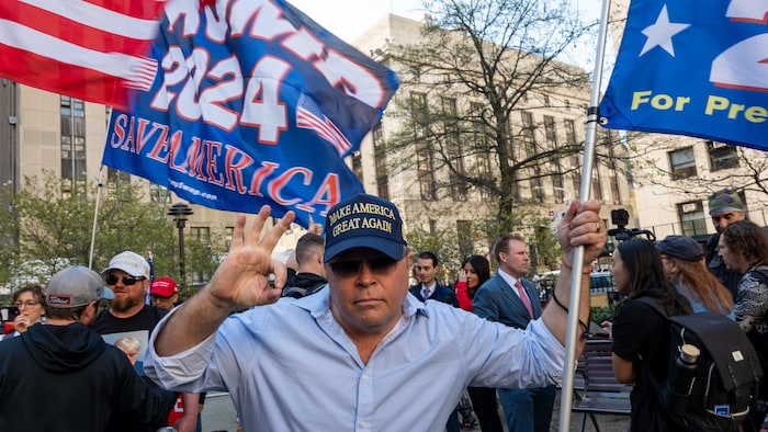 Un homme tient un drapeau sur lequel on lit «Trump pour président».