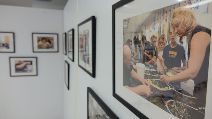 Un murs adorné de cadres avec des photos de personnes qui font de la peinture.