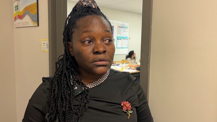 Carine Nno Endamane, le regard au loin, un groupe de personnes dans le fond.