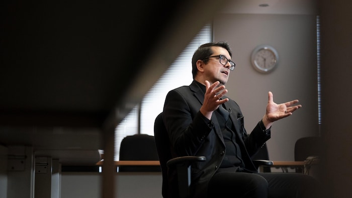 Assis sur une chaise, Simon Tremblay parle en ouvrant les mains.