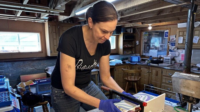 Une femme découpe des blocs de savon faits à base de lait de chèvre dans son atelier.
