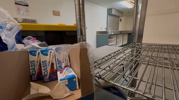Des boîtes de jus dans un carton posé sur une étagère.