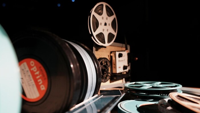 Des bobines de movie et un projecteur Super 8 dans un environnement sombre.